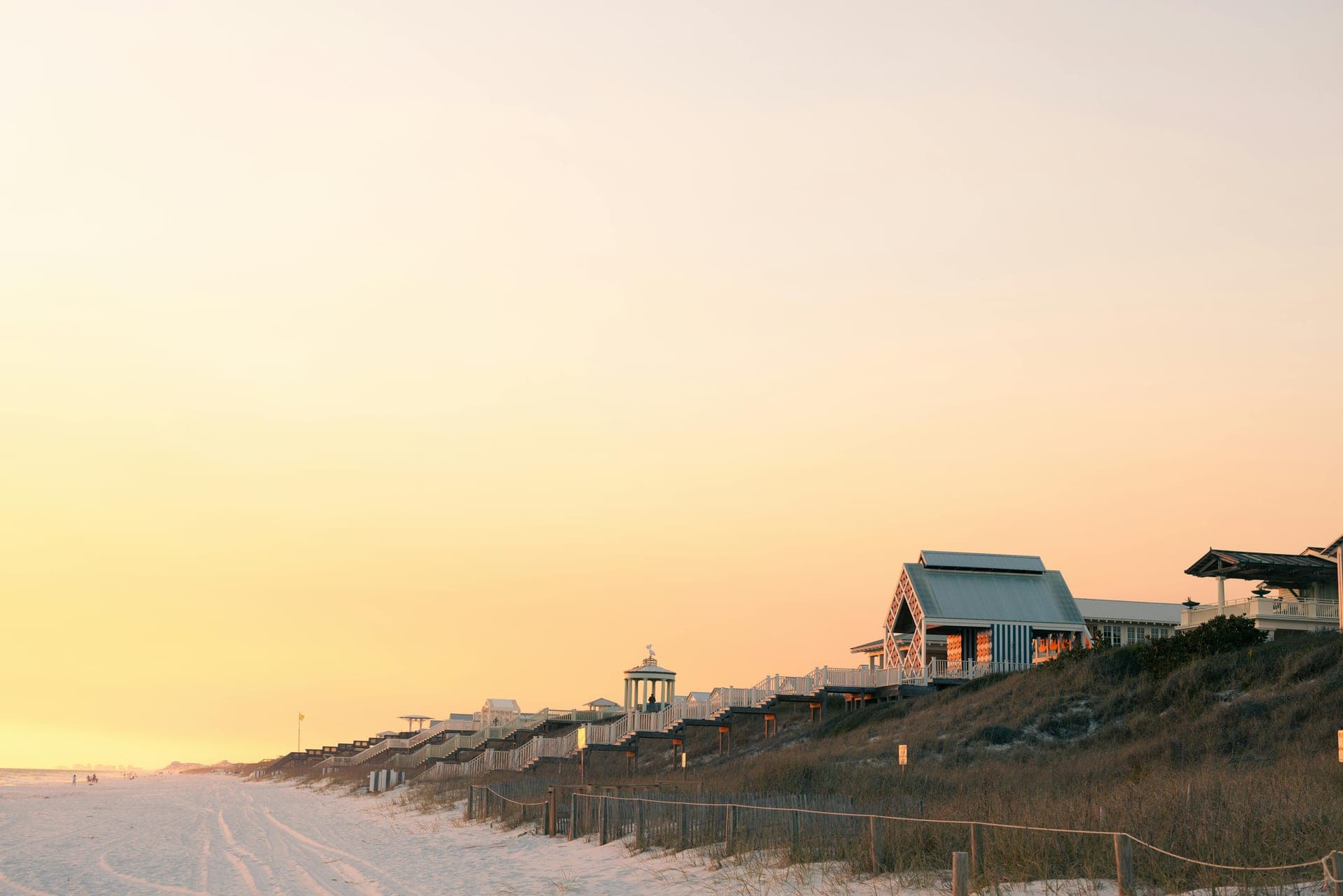 Row of 30A beach houses bathed in golden-hour light along the shoreline.