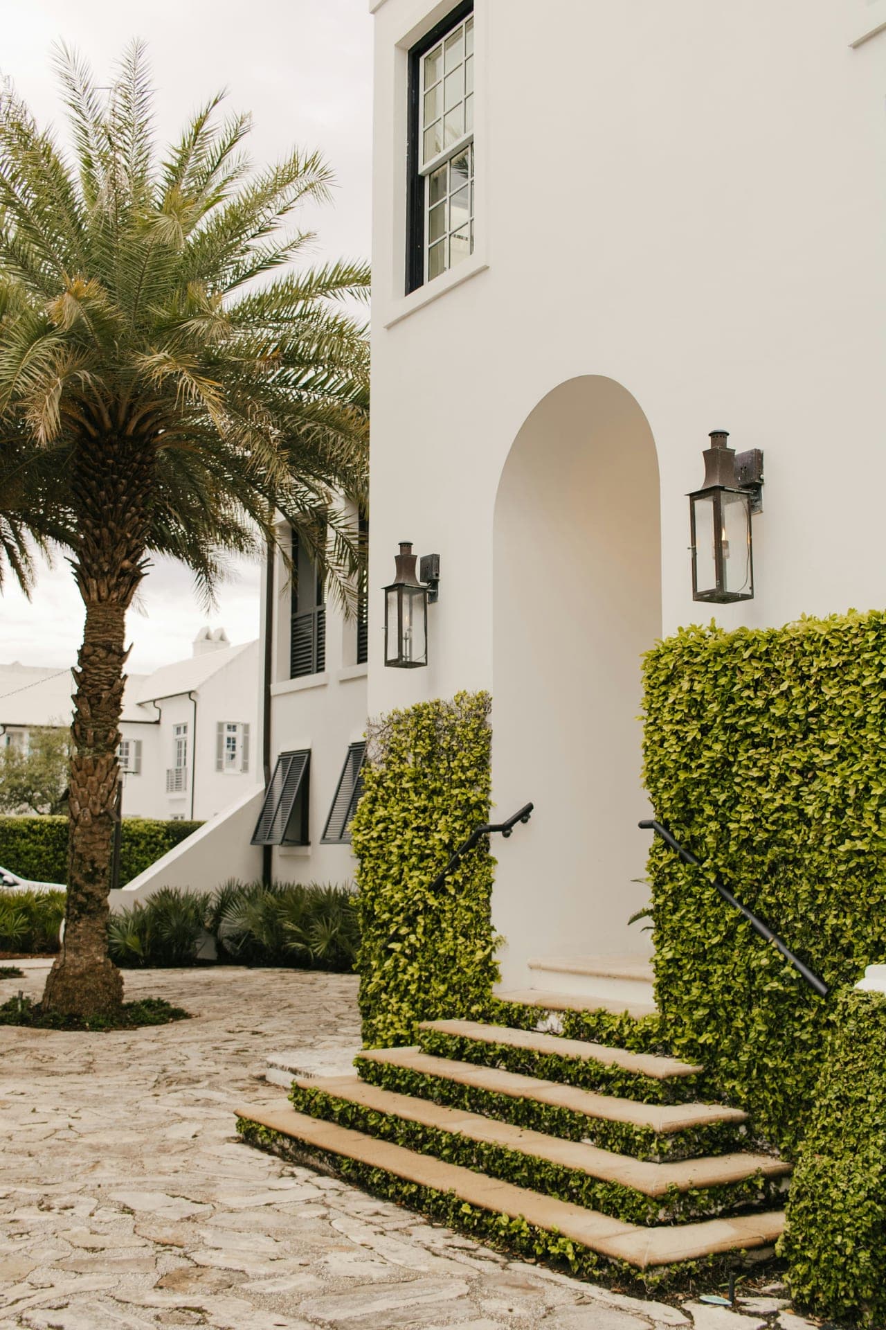 Alys Beach, FL — white stucco entry arch with palm and manicured planting.