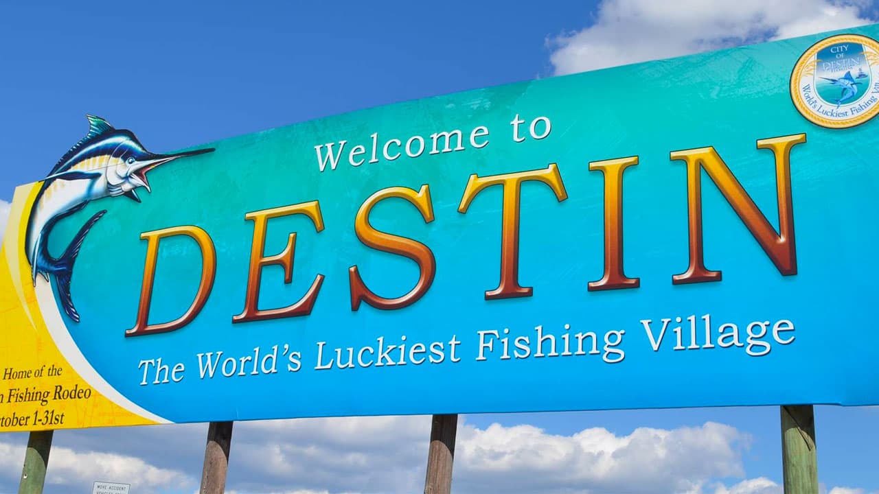 Highway sign reading 'Welcome to Destin — World's Luckiest Fishing Village'.